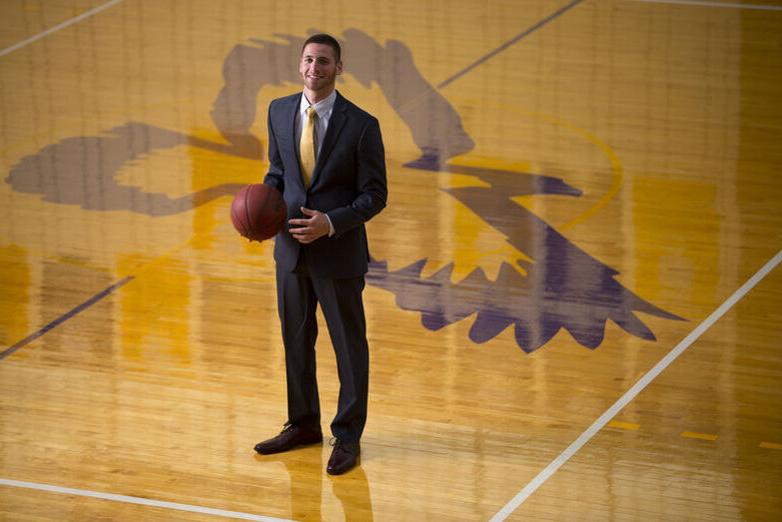 A man in a suit stands in the center of the basketball court
