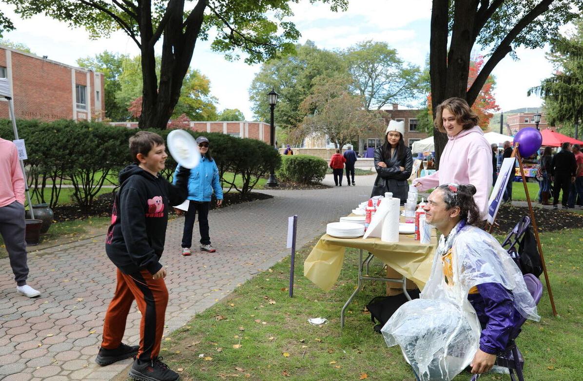 A boy throws a whipped cream pie at an Elmira College staff member during the Octagon Fair
